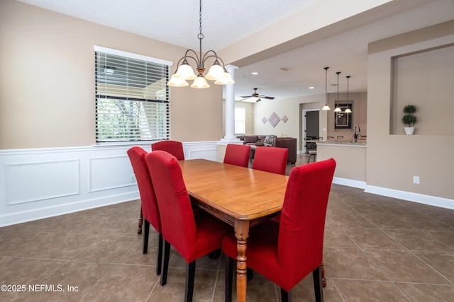 dining room featuring dark tile patterned floors, decorative columns, a decorative wall, and ceiling fan