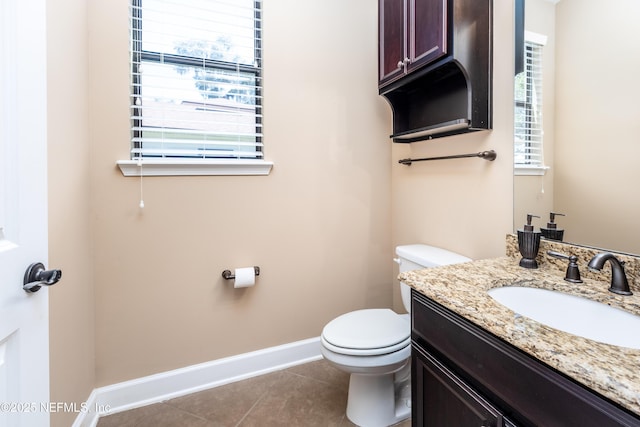 half bathroom with tile patterned flooring, baseboards, vanity, and toilet