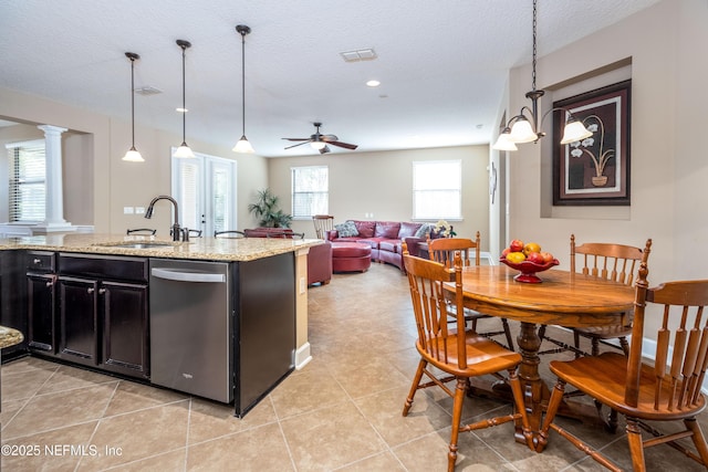 kitchen with a sink, visible vents, dark cabinetry, stainless steel dishwasher, and ornate columns