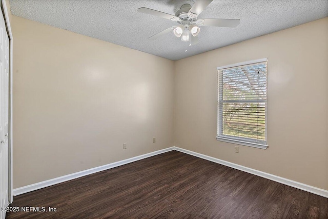 unfurnished room with a ceiling fan, a textured ceiling, baseboards, and dark wood-type flooring