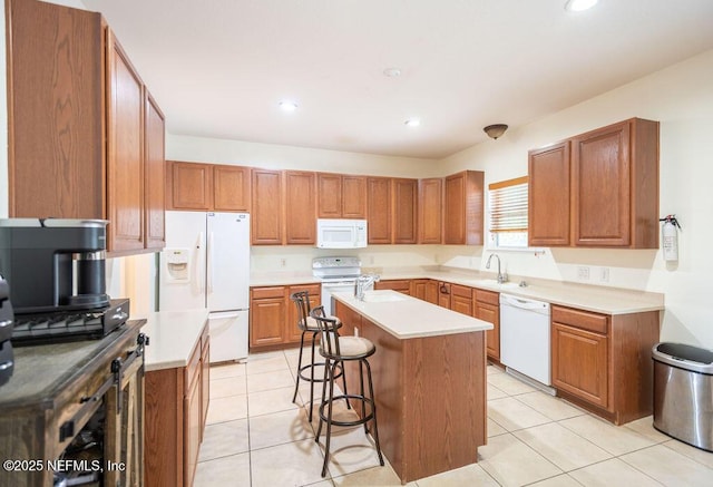 kitchen with light tile patterned floors, white appliances, brown cabinets, an island with sink, and a kitchen bar