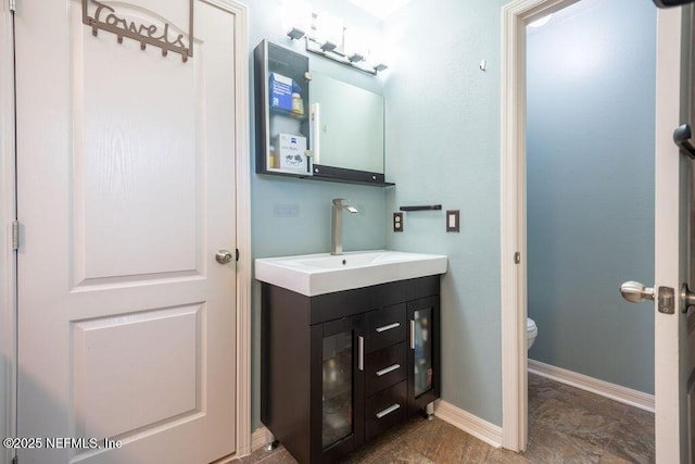 bathroom with vanity, toilet, and baseboards