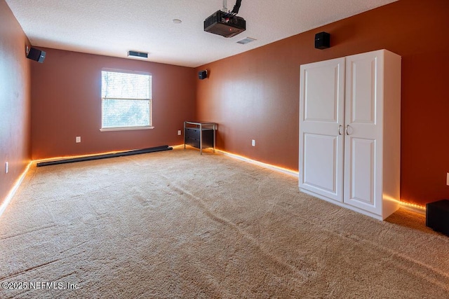 carpeted home theater with a textured ceiling, baseboard heating, visible vents, and baseboards