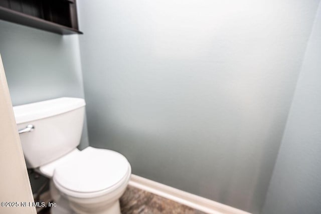 bathroom featuring toilet and baseboards