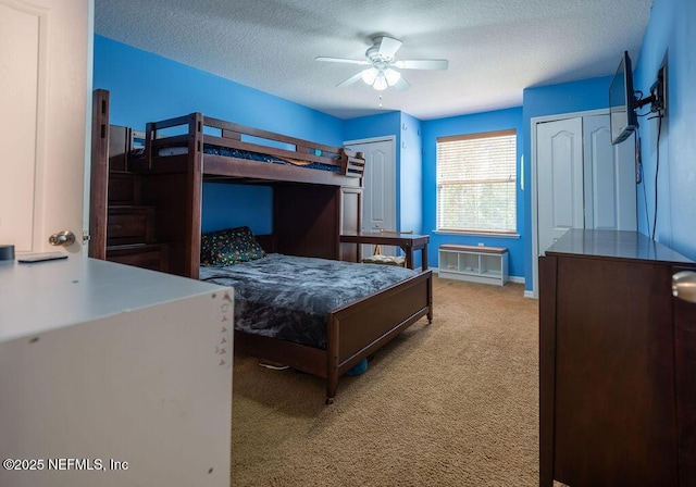 bedroom featuring a textured ceiling, carpet flooring, a ceiling fan, baseboards, and multiple closets