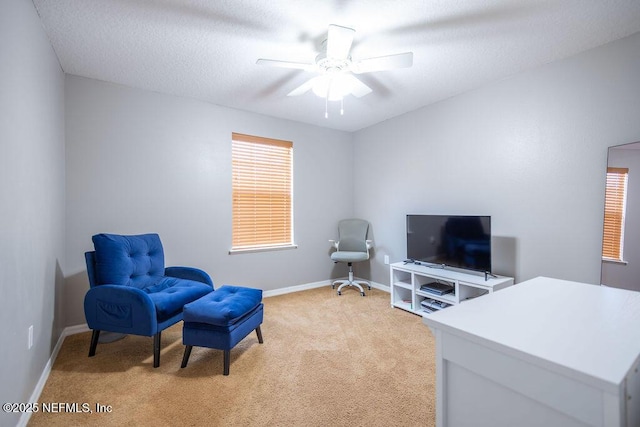 living area featuring baseboards, a textured ceiling, a ceiling fan, and light colored carpet