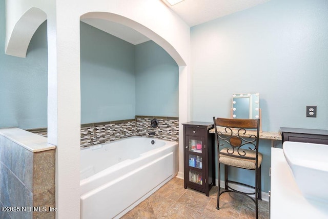 full bath with vanity, a bath, and baseboards