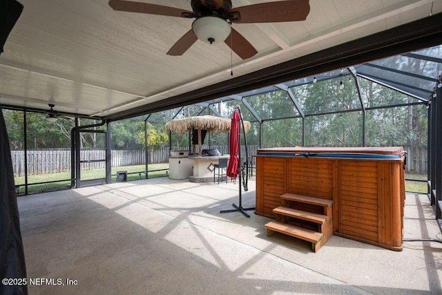 view of patio / terrace featuring a hot tub, glass enclosure, ceiling fan, outdoor dry bar, and fence