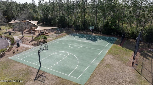 view of basketball court with community basketball court, a forest view, and fence