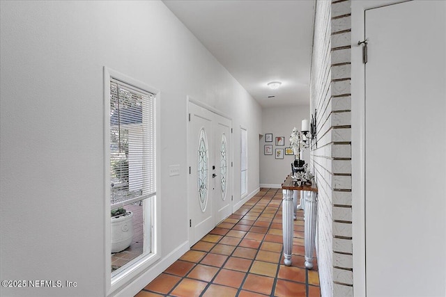 corridor featuring light tile patterned flooring and baseboards