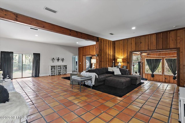 living area with light tile patterned floors, wood walls, beamed ceiling, and visible vents