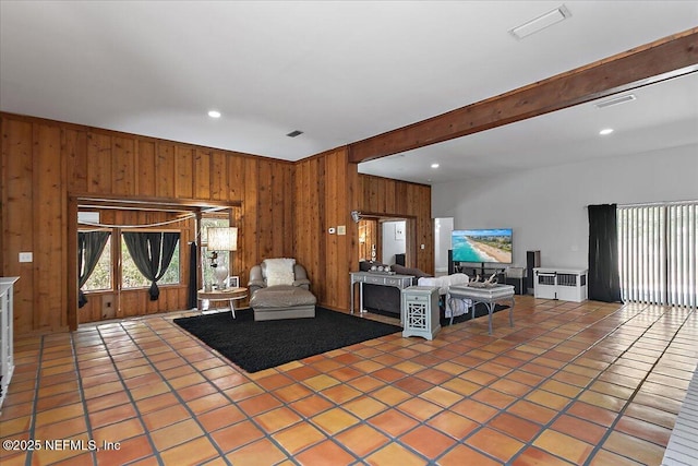 unfurnished living room featuring beam ceiling, light tile patterned floors, recessed lighting, visible vents, and wood walls