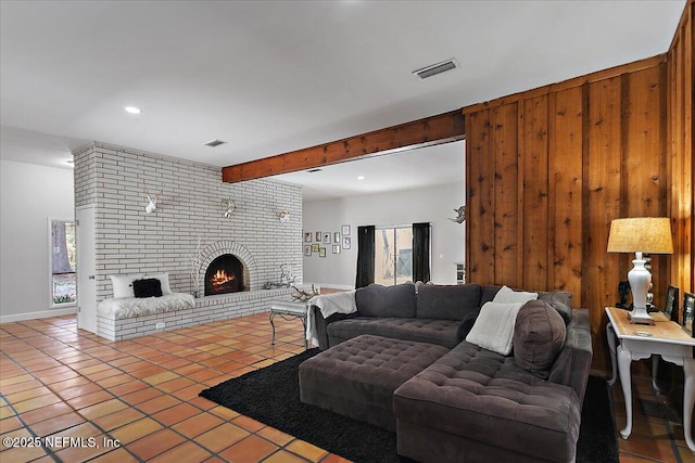 living area with tile patterned flooring, a fireplace, visible vents, and beam ceiling