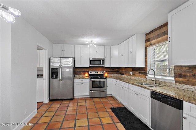 kitchen featuring light stone counters, tasteful backsplash, appliances with stainless steel finishes, white cabinets, and a sink