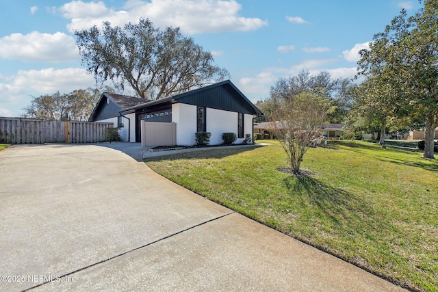 view of side of home with a garage, a yard, fence, and driveway