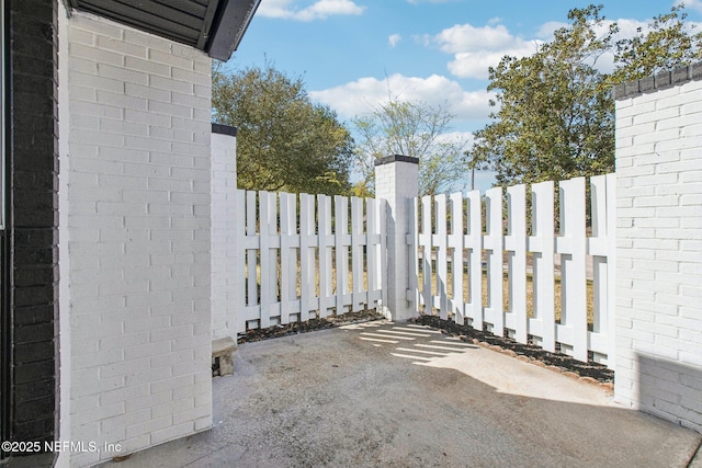 view of gate featuring fence and a patio