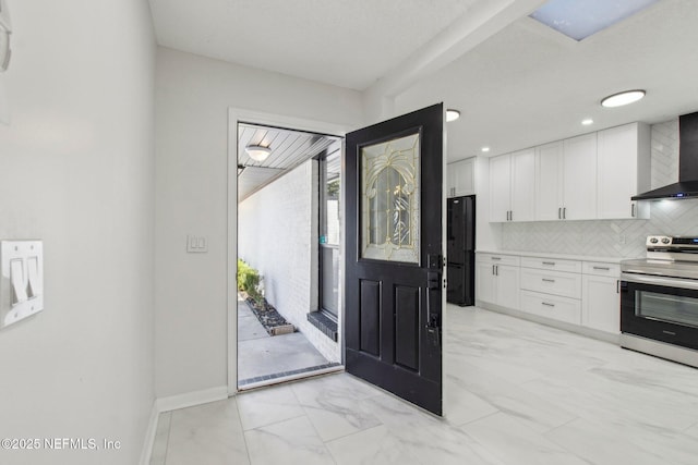 kitchen featuring electric range, decorative backsplash, freestanding refrigerator, marble finish floor, and white cabinetry