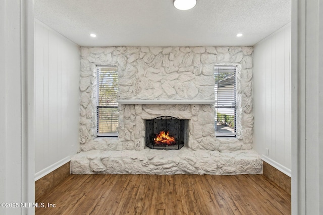 unfurnished living room with a textured ceiling, a fireplace, and wood finished floors