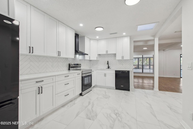 kitchen with marble finish floor, decorative backsplash, white cabinets, black appliances, and wall chimney exhaust hood