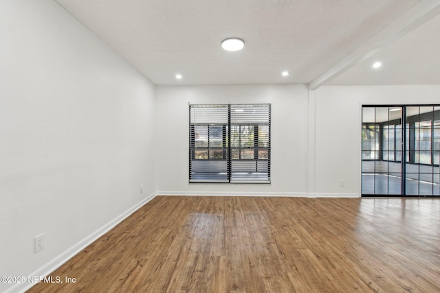 unfurnished room featuring plenty of natural light, baseboards, and wood finished floors