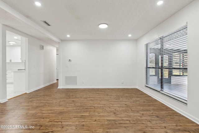 spare room with recessed lighting, visible vents, baseboards, and wood finished floors