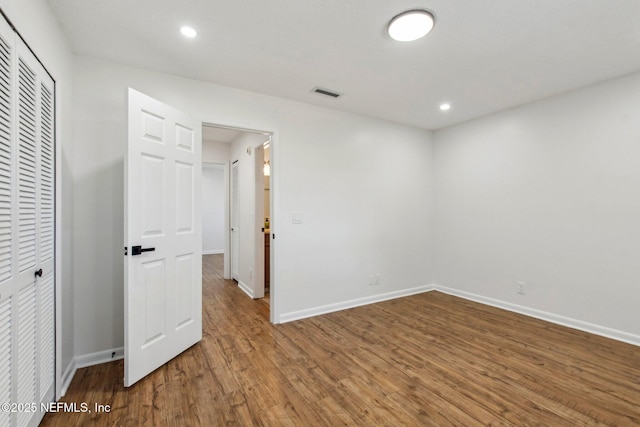 unfurnished bedroom with recessed lighting, a closet, visible vents, wood finished floors, and baseboards