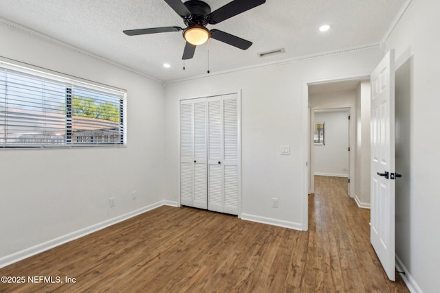 unfurnished bedroom with visible vents, a textured ceiling, and wood finished floors