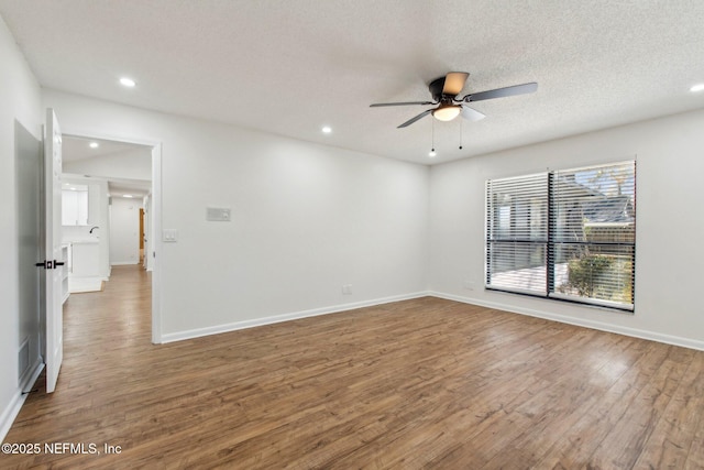 spare room with a textured ceiling, wood finished floors, a ceiling fan, and recessed lighting