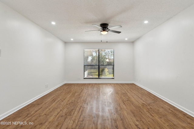 spare room with a textured ceiling, recessed lighting, wood finished floors, a ceiling fan, and baseboards