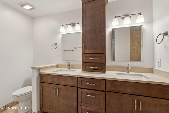 full bath featuring visible vents, a sink, toilet, and double vanity