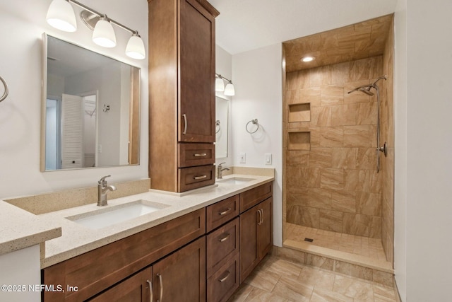 bathroom with double vanity, tiled shower, and a sink