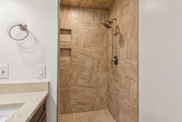 bathroom with tiled shower and vanity