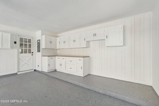 kitchen featuring a textured ceiling, speckled floor, and electric panel