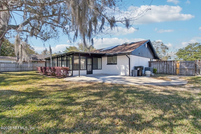 back of house with a fenced backyard, a gate, a yard, a patio area, and roof mounted solar panels