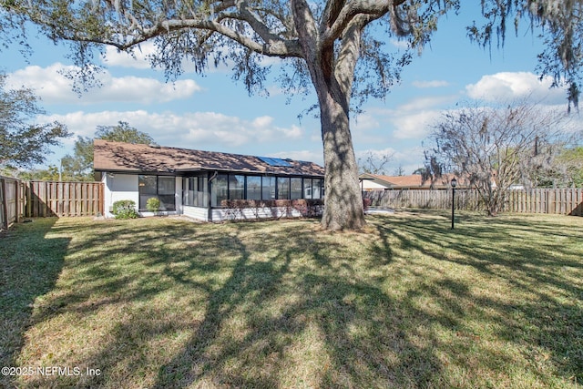 view of yard featuring a sunroom and a fenced backyard