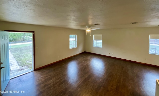 spare room with a textured ceiling, wood finished floors, visible vents, and baseboards