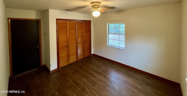 unfurnished bedroom with dark wood-style floors, a closet, baseboards, and a ceiling fan