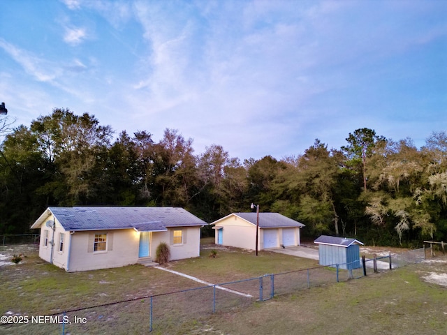 view of front of home with a front yard, entry steps, fence, a garage, and an outdoor structure