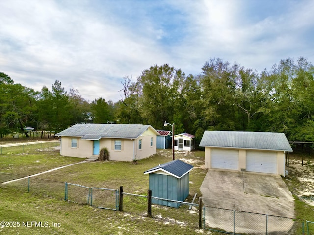 exterior space with a detached garage, an outdoor structure, fence, a gate, and a front yard