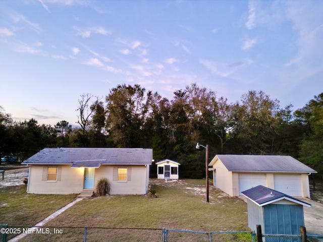 view of front of home featuring an outbuilding, fence, and a front lawn