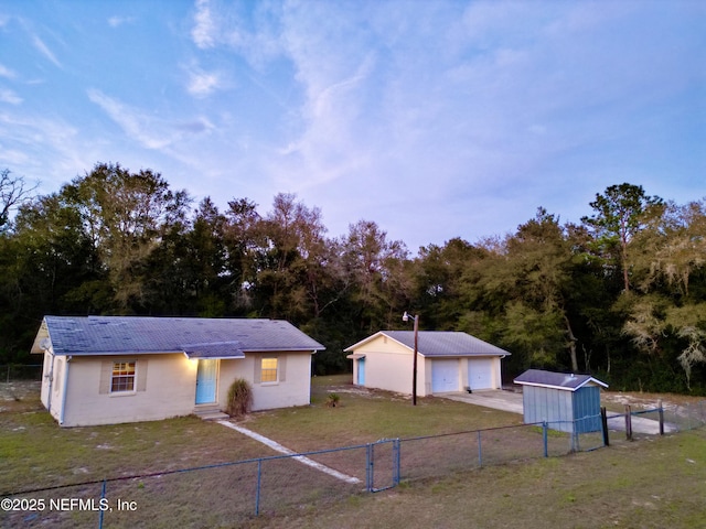 view of front of home featuring an outbuilding, entry steps, a detached garage, fence, and a front yard