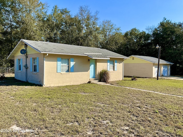 single story home with a garage, concrete block siding, an outbuilding, fence, and a front lawn