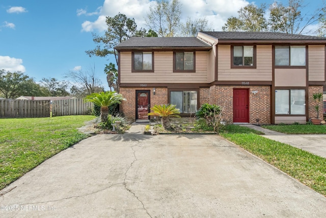 view of front of house featuring a front yard, fence, and brick siding