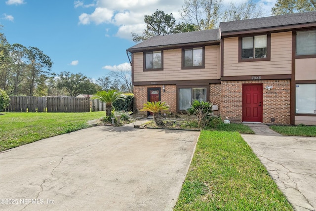 view of front of house with a front yard, brick siding, and fence