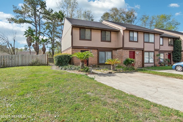 view of property featuring a front yard, brick siding, and fence