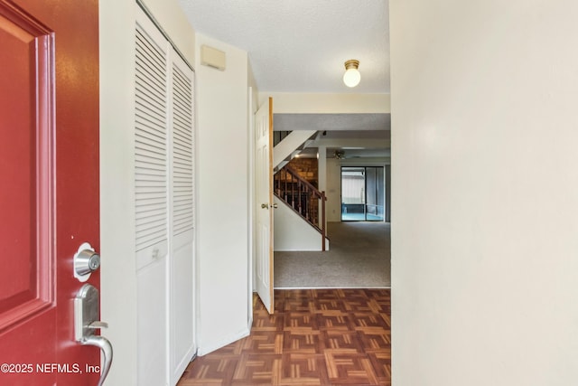 hall with stairway and a textured ceiling