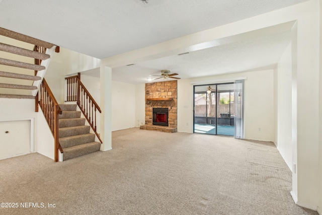 unfurnished living room with carpet flooring, a fireplace, and stairs