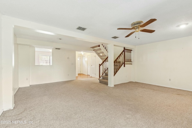 below grade area featuring stairs, a textured ceiling, light carpet, and visible vents