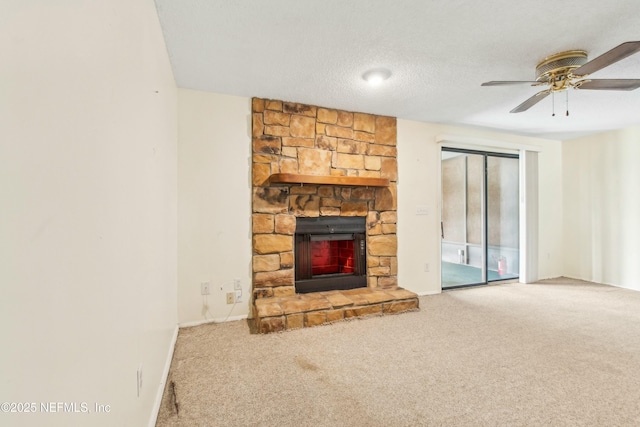 unfurnished living room featuring a ceiling fan, carpet, a stone fireplace, and a textured ceiling