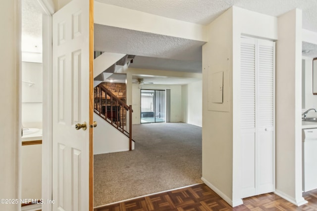 hallway with carpet floors, a textured ceiling, and stairs